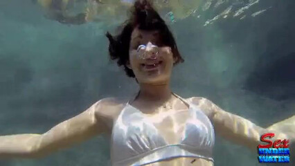 Брюнетка плавает голой в бассейне и ласкает свои прелести